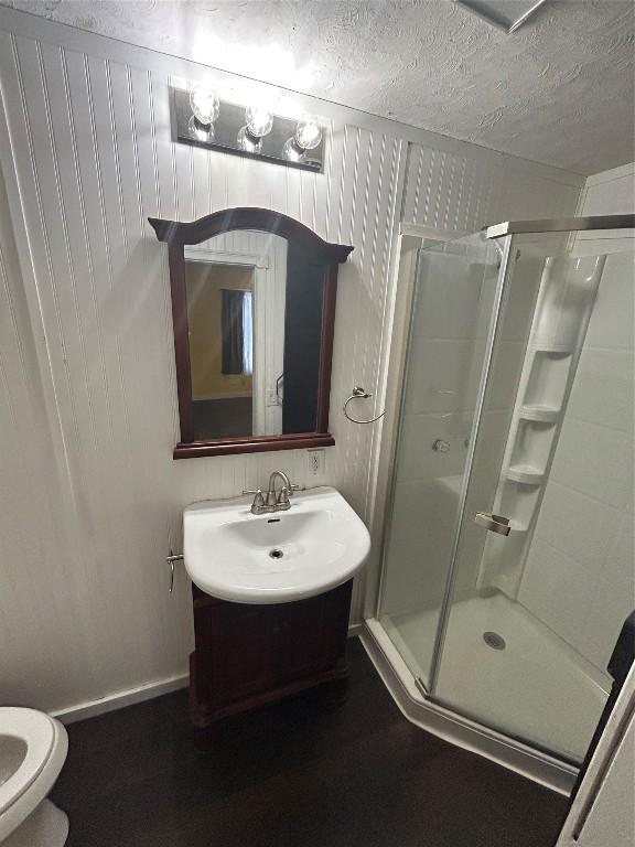 bathroom with toilet, an enclosed shower, a textured ceiling, and vanity