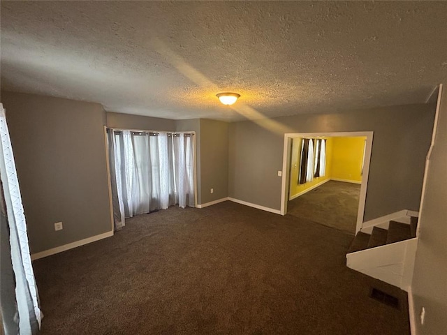 unfurnished room with dark carpet and a textured ceiling