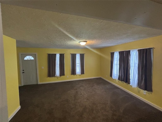 empty room featuring dark carpet and a textured ceiling