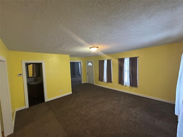 unfurnished room with dark colored carpet and a textured ceiling