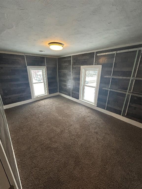 carpeted empty room with a textured ceiling