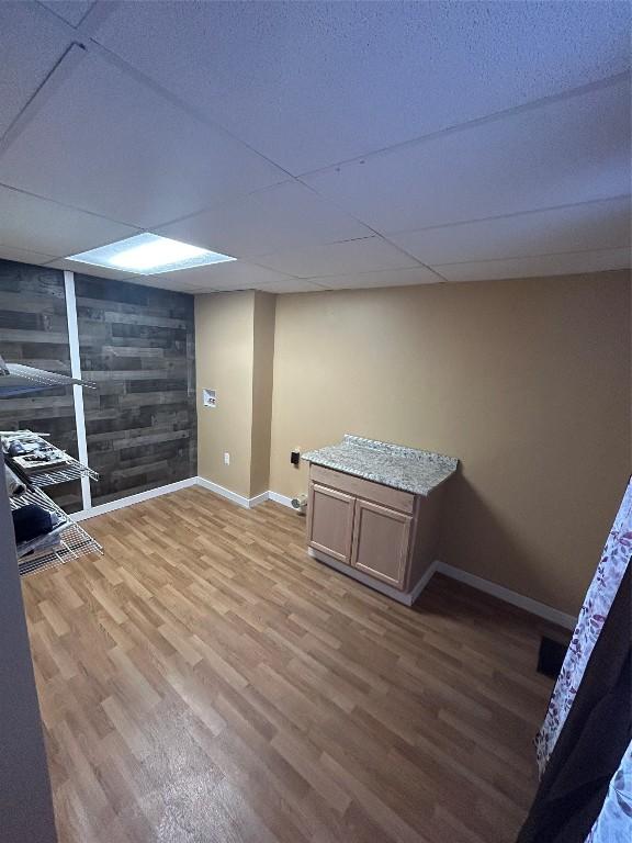 basement with a drop ceiling and wood-type flooring