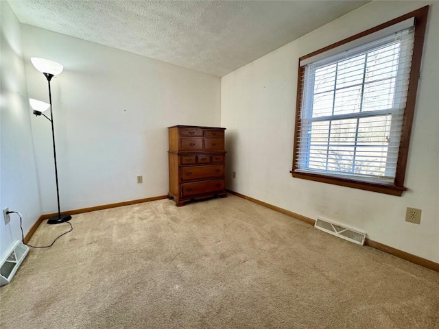 unfurnished bedroom featuring light carpet, baseboards, visible vents, and a textured ceiling