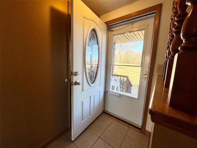 doorway to outside featuring a textured ceiling and light tile patterned flooring