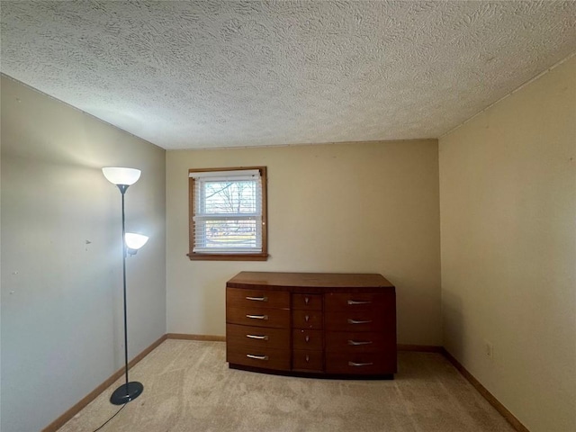 unfurnished bedroom with light carpet, a textured ceiling, and baseboards