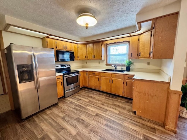 kitchen with light wood-style floors, stainless steel appliances, a sink, and light countertops