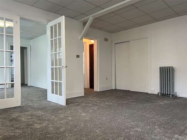 empty room featuring dark carpet, radiator, and french doors