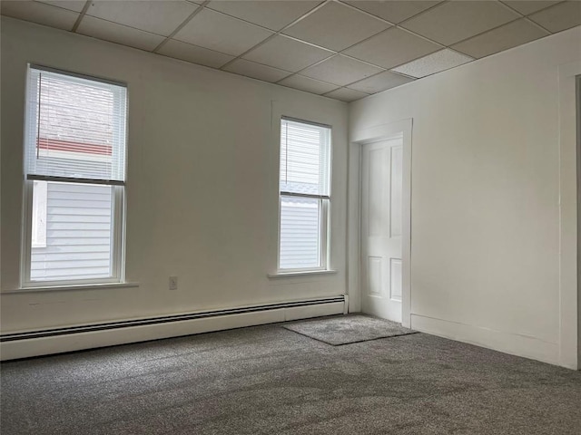 carpeted spare room featuring a paneled ceiling and a baseboard heating unit