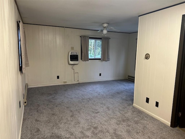 carpeted spare room with heating unit, wood walls, ceiling fan, and a baseboard radiator