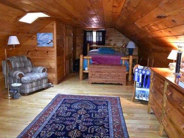 bedroom featuring light hardwood / wood-style floors, lofted ceiling with skylight, wood walls, and wood ceiling