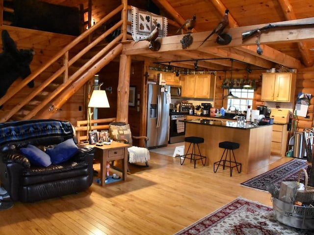 living room with wood walls, vaulted ceiling with beams, light hardwood / wood-style floors, and wood ceiling