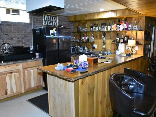 bar featuring black refrigerator and light brown cabinets