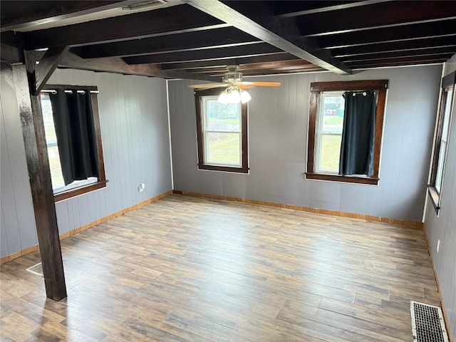 unfurnished room featuring beam ceiling, ceiling fan, light hardwood / wood-style flooring, and plenty of natural light