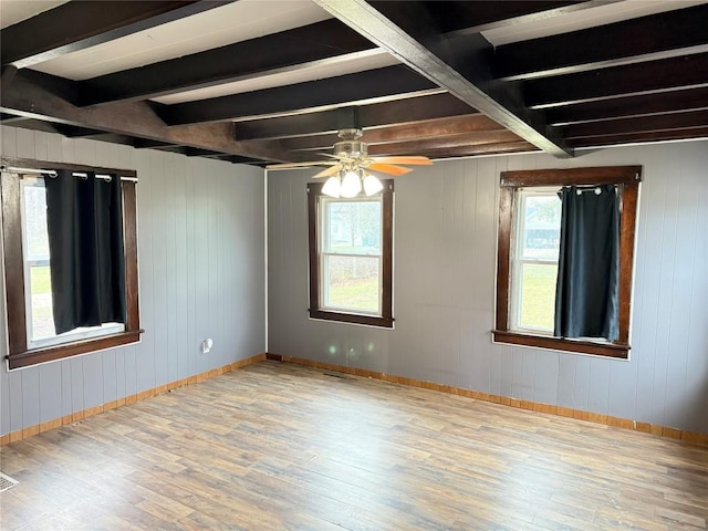 unfurnished room with wood walls, ceiling fan, beam ceiling, and light wood-type flooring