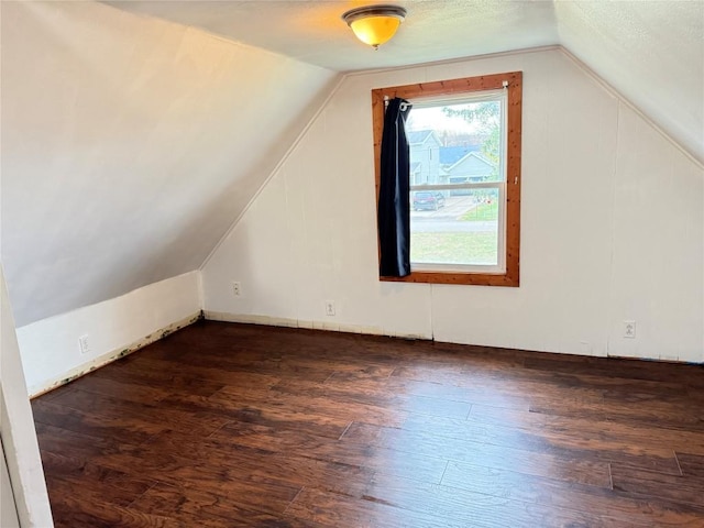 bonus room with a textured ceiling, dark wood-type flooring, and vaulted ceiling