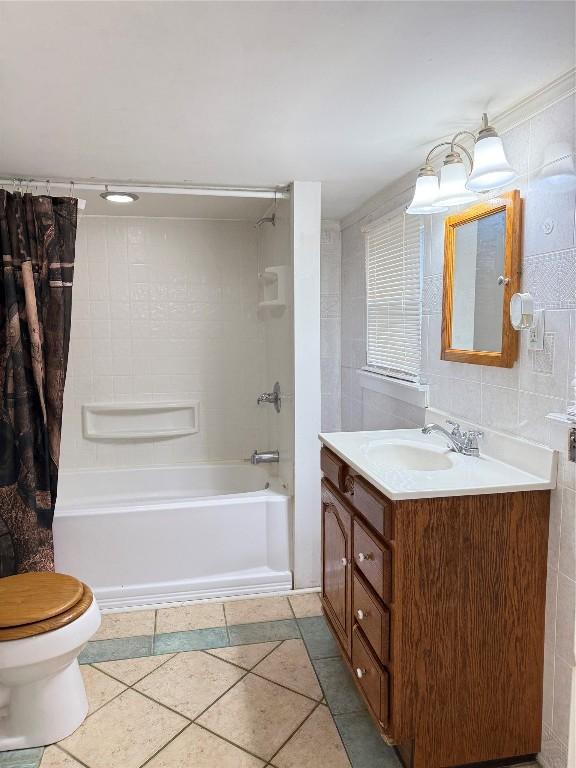 full bathroom with shower / tub combo, tile patterned floors, toilet, vanity, and tile walls