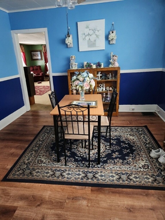 dining room with wood-type flooring and crown molding