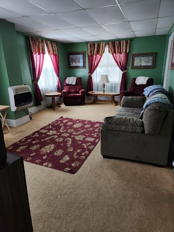 carpeted living room with a paneled ceiling and heating unit