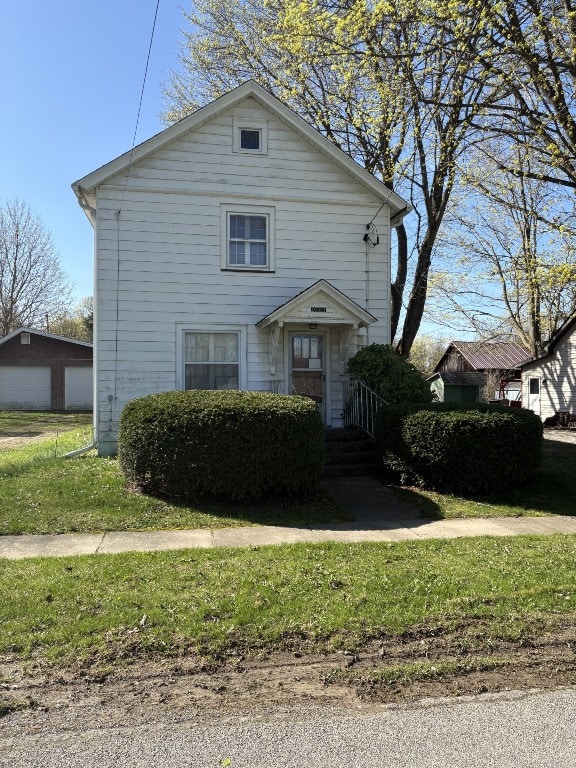 view of front of property featuring a detached garage and a front lawn