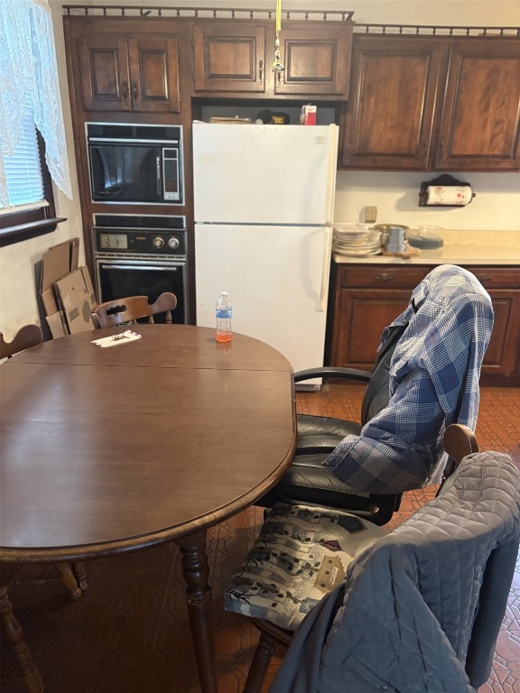 kitchen with black microwave, stainless steel oven, and freestanding refrigerator