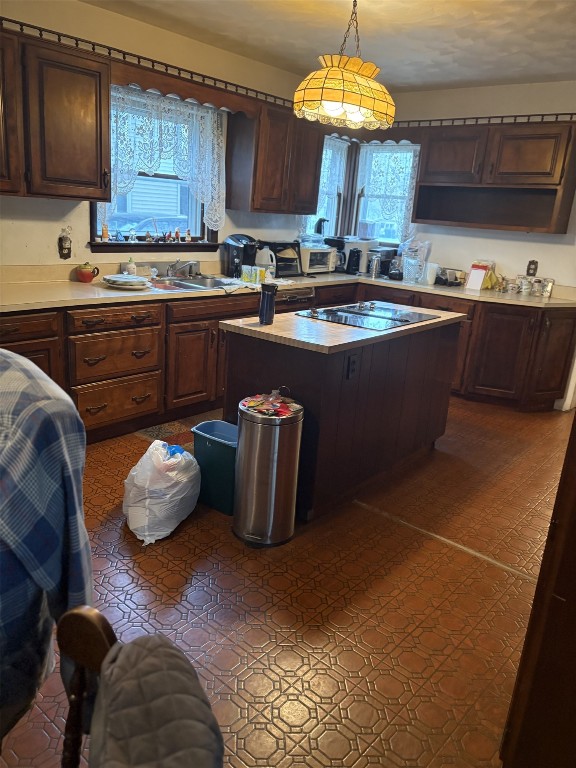 kitchen with a center island, dark brown cabinetry, a sink, and light countertops