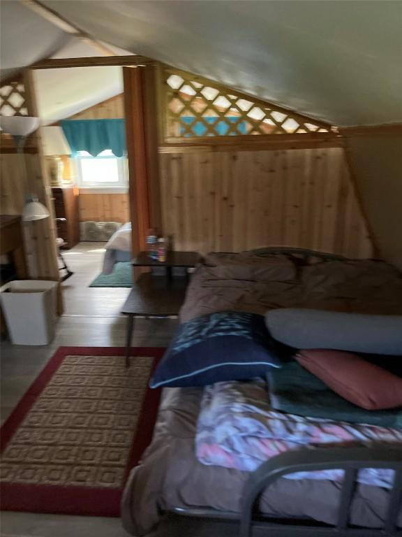 bedroom with wooden walls and lofted ceiling