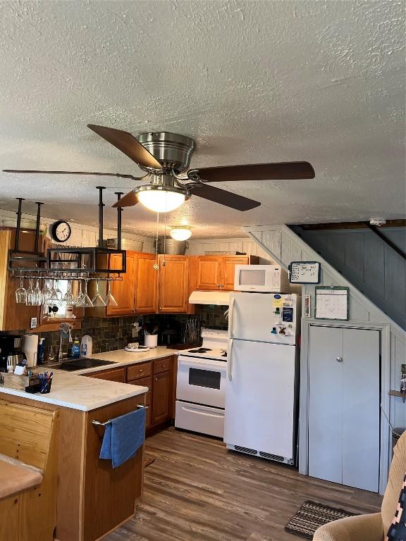 kitchen with white appliances, a textured ceiling, and a sink