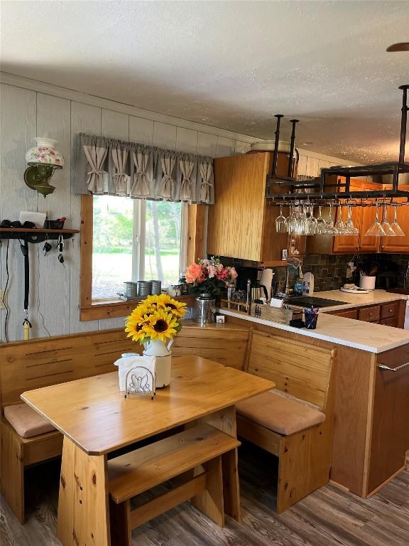 kitchen with decorative backsplash, wood finished floors, light countertops, brown cabinets, and a sink