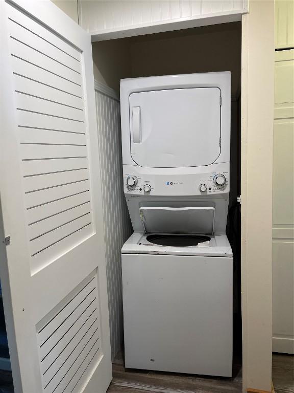 washroom featuring stacked washer and dryer, laundry area, and wood finished floors