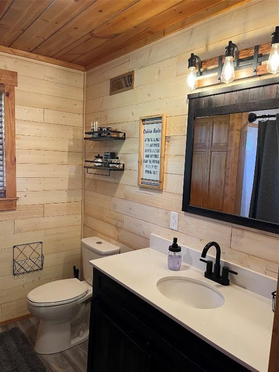 bathroom featuring wood ceiling, vanity, wood walls, and toilet