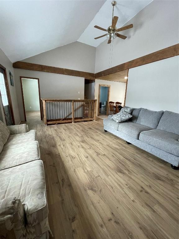 living area with ceiling fan, high vaulted ceiling, and wood finished floors