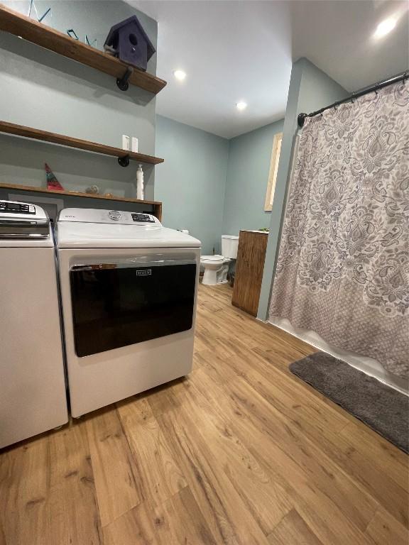 clothes washing area with laundry area, washer and clothes dryer, light wood-style flooring, and recessed lighting