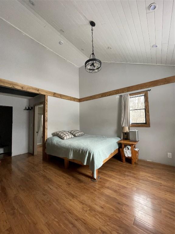 unfurnished bedroom with wooden ceiling, vaulted ceiling, and wood finished floors