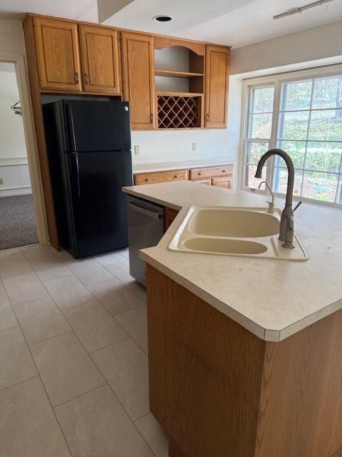 kitchen featuring a sink, open shelves, freestanding refrigerator, light countertops, and dishwasher