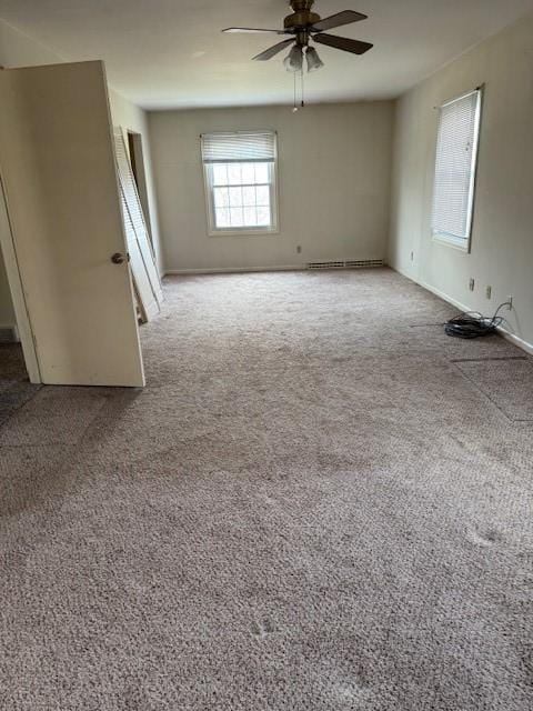 carpeted empty room with a baseboard heating unit, baseboards, and ceiling fan