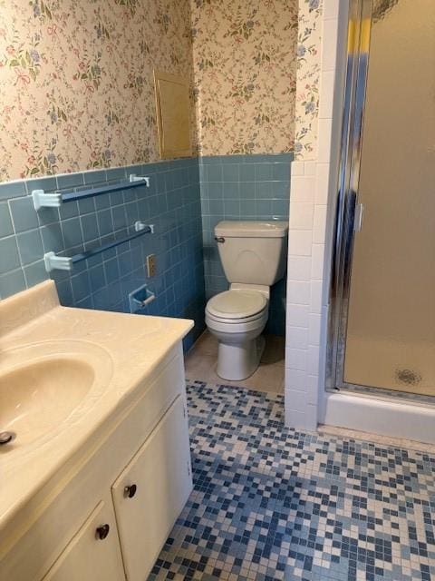 full bath with wallpapered walls, tile patterned floors, a stall shower, and wainscoting