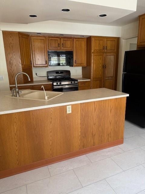 kitchen with brown cabinets, black appliances, light countertops, and a sink