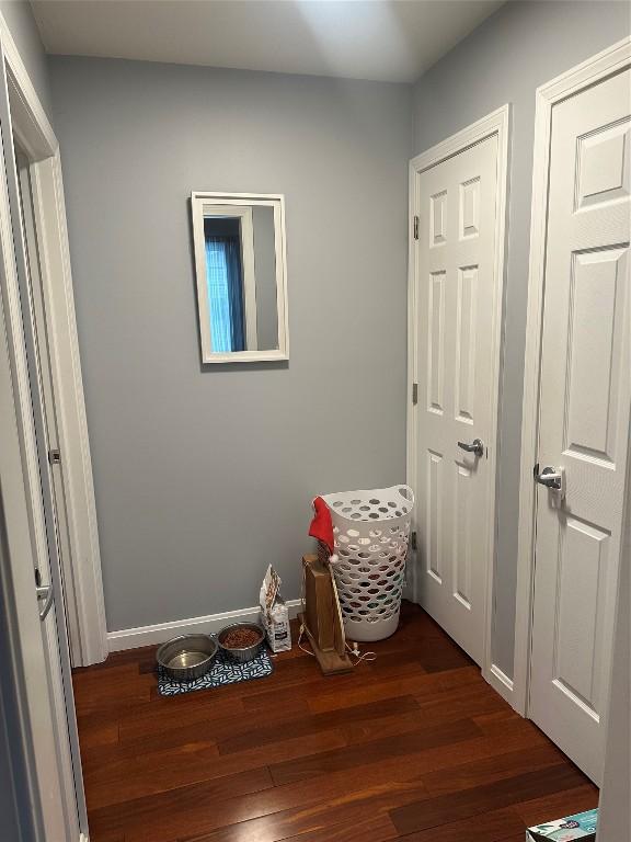 corridor with baseboards and wood finished floors