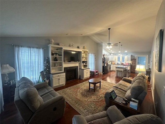 living room with ceiling fan, a fireplace, vaulted ceiling, and dark wood finished floors