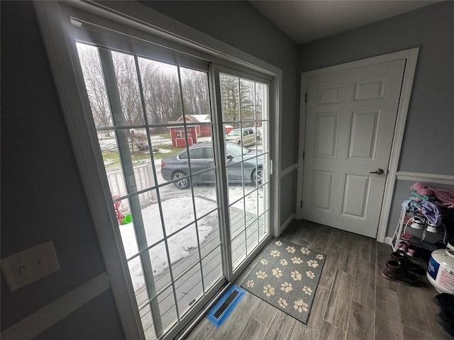 doorway with wood finish floors, visible vents, and baseboards