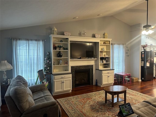 living area featuring lofted ceiling, a fireplace, dark wood finished floors, and a ceiling fan