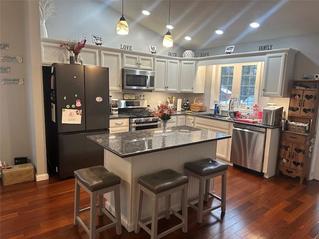 kitchen featuring vaulted ceiling, stainless steel appliances, dark wood-style flooring, and a kitchen breakfast bar