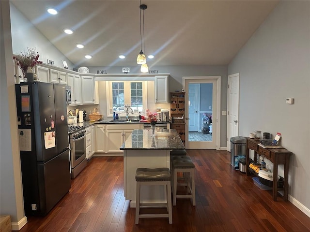 kitchen featuring dark wood-style floors, appliances with stainless steel finishes, vaulted ceiling, pendant lighting, and a sink