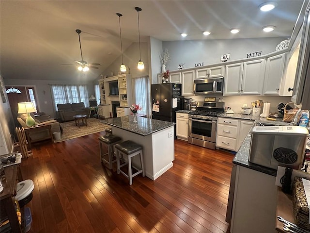 kitchen featuring dark wood-style floors, appliances with stainless steel finishes, a kitchen island, a sink, and ceiling fan