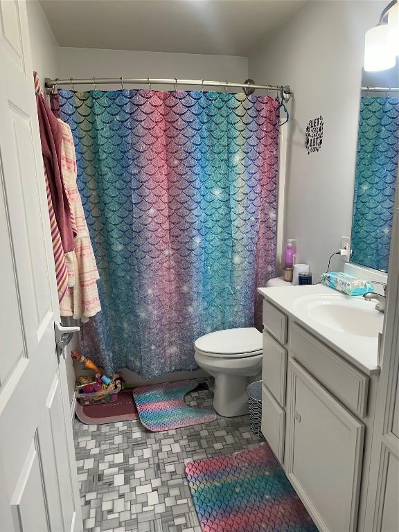 bathroom featuring toilet, a shower with shower curtain, and vanity