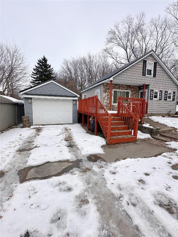 view of snow covered exterior with an outbuilding, a garage, and a deck