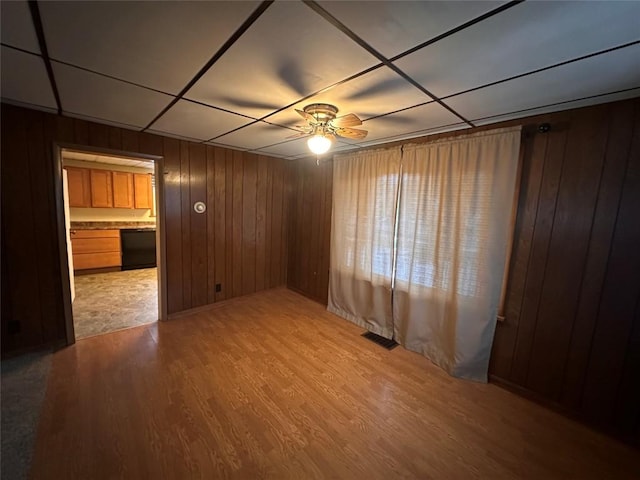 spare room with ceiling fan, light hardwood / wood-style floors, and wood walls