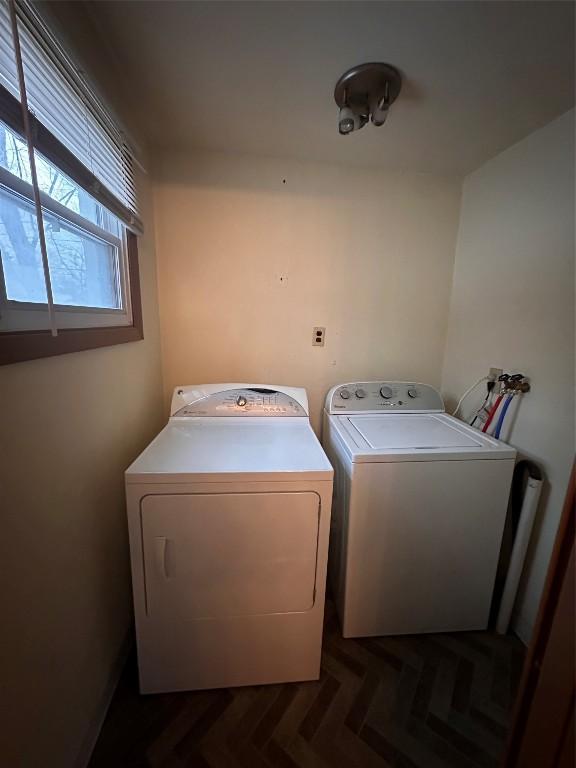 clothes washing area featuring washer and clothes dryer and dark parquet floors