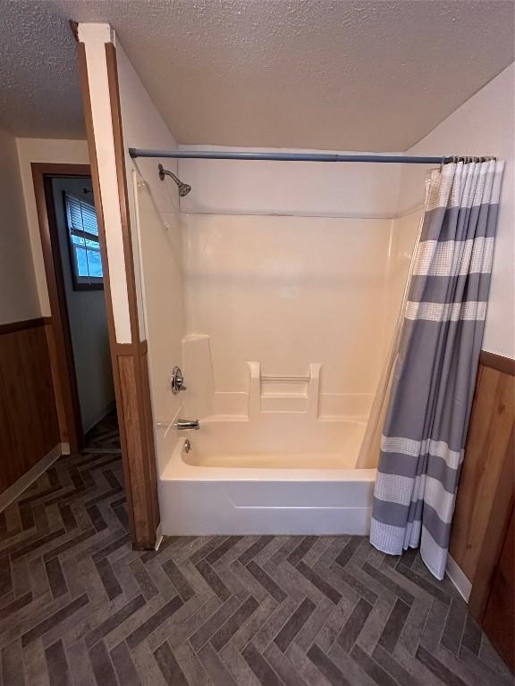 bathroom with shower / bath combination with curtain and a textured ceiling