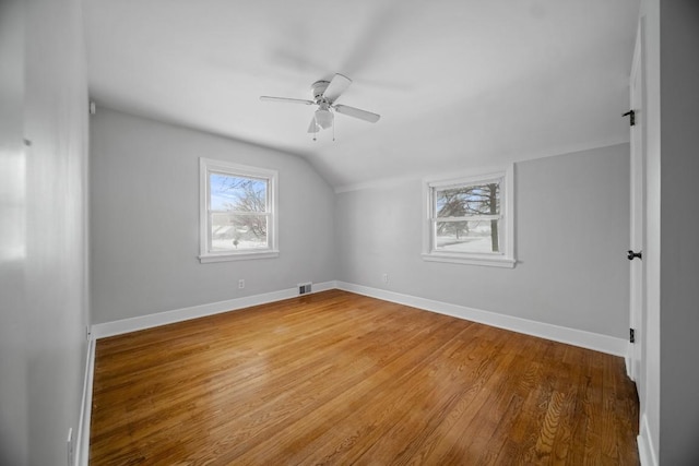 additional living space with ceiling fan, vaulted ceiling, a wealth of natural light, and hardwood / wood-style floors